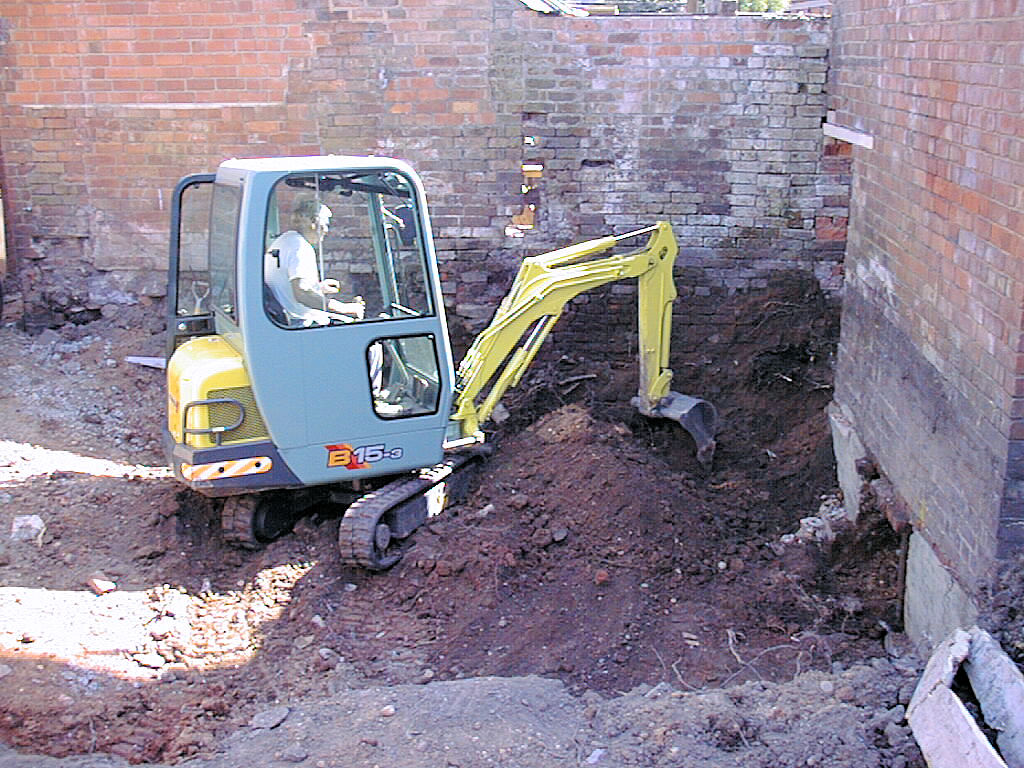 a JCB digging the tree from under the wall